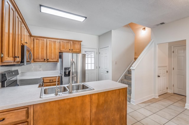 kitchen with light tile patterned floors, sink, appliances with stainless steel finishes, and kitchen peninsula