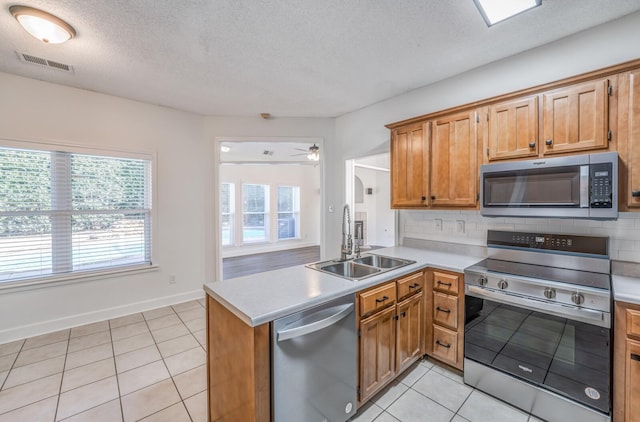 kitchen with light tile patterned floors, decorative backsplash, sink, kitchen peninsula, and stainless steel appliances