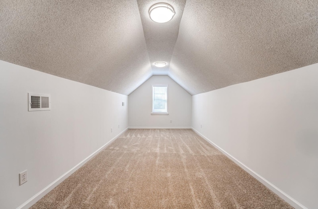 bonus room featuring a textured ceiling, light carpet, and vaulted ceiling