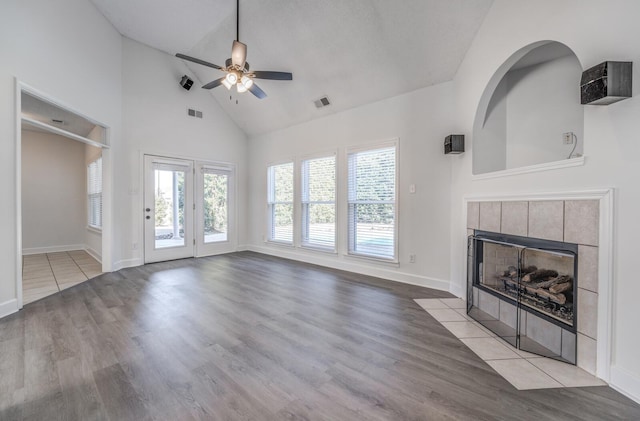 unfurnished living room with ceiling fan, plenty of natural light, a tile fireplace, and light hardwood / wood-style flooring