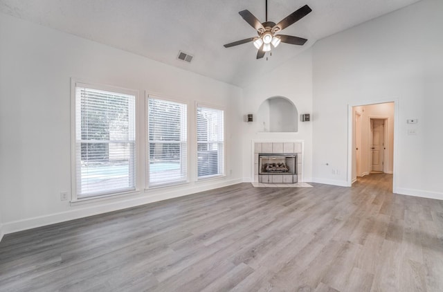 unfurnished living room with a tile fireplace, light hardwood / wood-style floors, and a healthy amount of sunlight