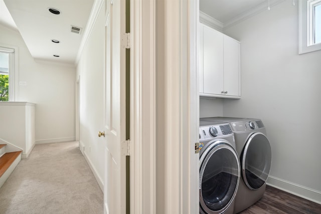 clothes washing area featuring light colored carpet, ornamental molding, cabinets, and washer and dryer