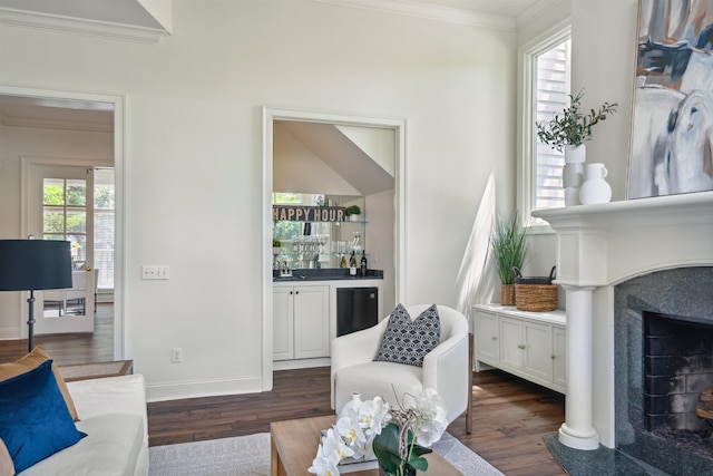 living room featuring wet bar, a high end fireplace, crown molding, and dark wood-type flooring