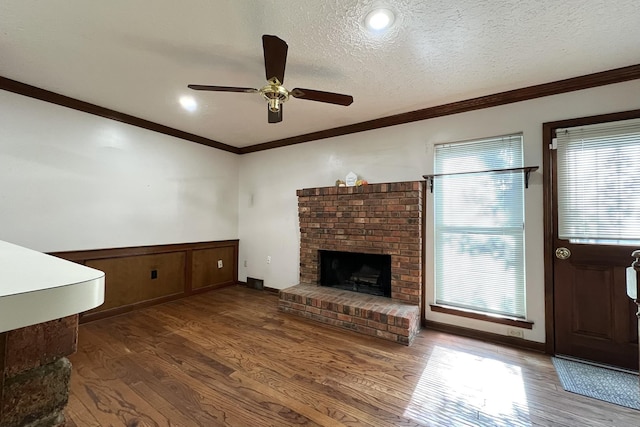 unfurnished living room with crown molding, a brick fireplace, dark wood-type flooring, and a textured ceiling