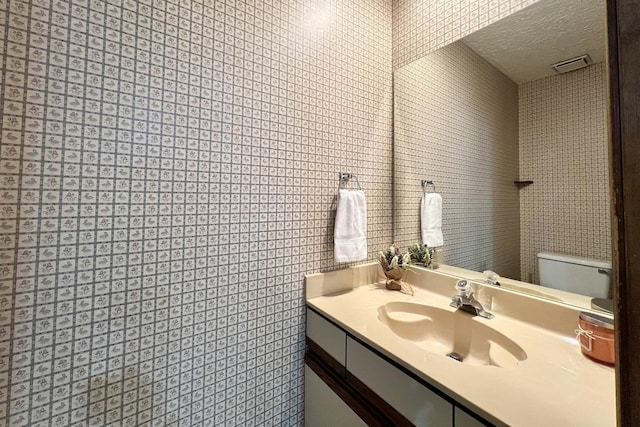 bathroom with vanity, a textured ceiling, and toilet