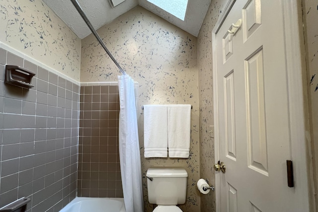 bathroom featuring shower / tub combo with curtain, a skylight, toilet, and a textured ceiling