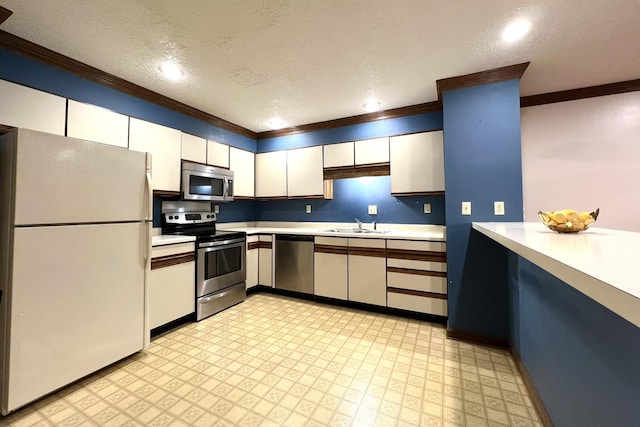 kitchen with sink, white cabinetry, stainless steel appliances, ornamental molding, and a textured ceiling