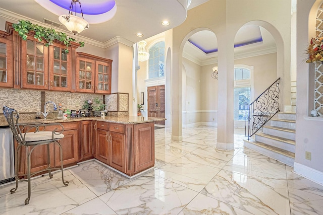 kitchen featuring crown molding, pendant lighting, tasteful backsplash, light stone countertops, and a tray ceiling