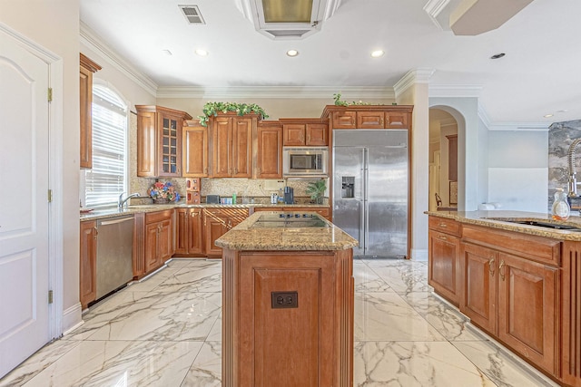 kitchen with a kitchen island, built in appliances, decorative backsplash, ornamental molding, and light stone counters