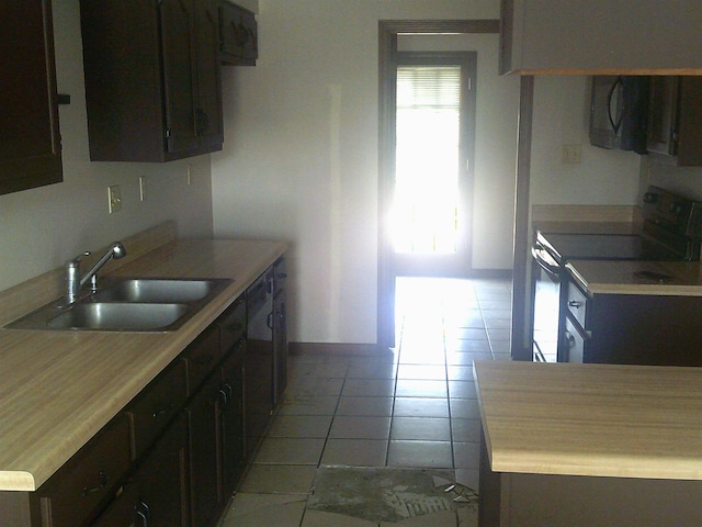 kitchen featuring light tile patterned flooring, sink, electric range, and dark brown cabinetry