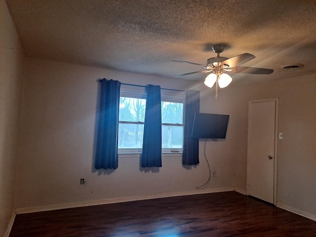 empty room featuring ceiling fan, dark hardwood / wood-style flooring, and a textured ceiling