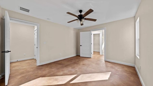 unfurnished bedroom featuring a closet, ceiling fan, a spacious closet, and light carpet