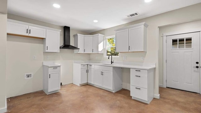 kitchen with sink, wall chimney range hood, and white cabinets