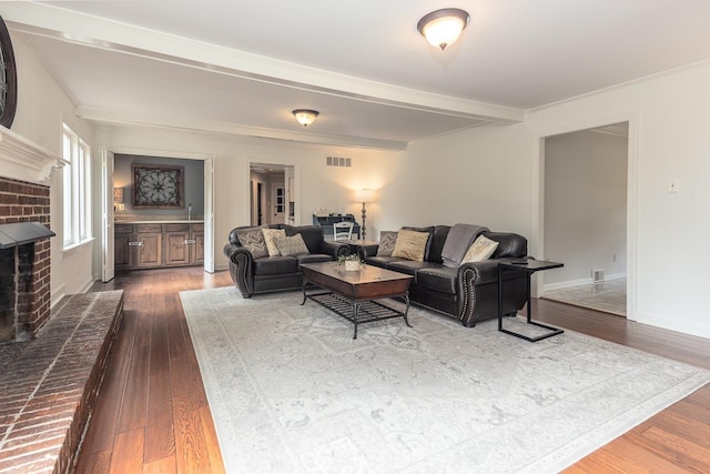 living room with hardwood / wood-style flooring, a fireplace, and beamed ceiling