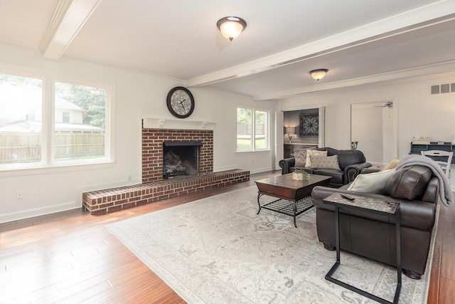 living room with beamed ceiling, a fireplace, and light hardwood / wood-style flooring