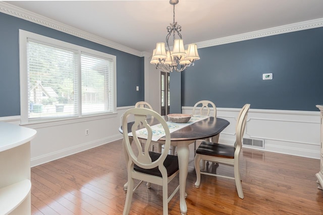 dining area featuring crown molding, dark hardwood / wood-style floors, and a chandelier