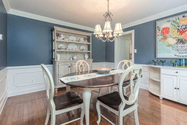 dining area featuring hardwood / wood-style floors, crown molding, and a chandelier