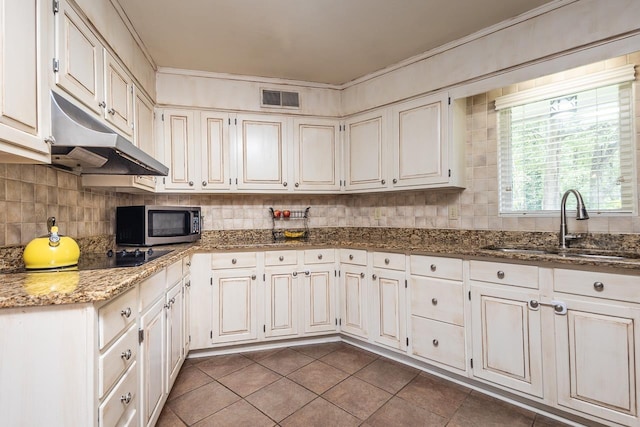 kitchen with sink, dark tile patterned floors, white cabinetry, dark stone countertops, and black electric cooktop