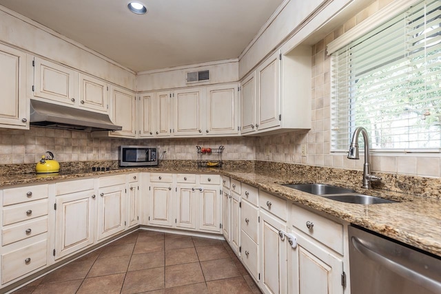 kitchen featuring sink, stainless steel appliances, light stone countertops, white cabinets, and dark tile patterned flooring