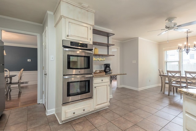 kitchen featuring cream cabinets, light tile patterned floors, ornamental molding, and stainless steel double oven