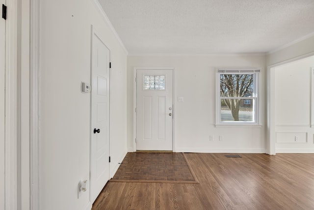 entrance foyer with dark hardwood / wood-style flooring, ornamental molding, and a textured ceiling