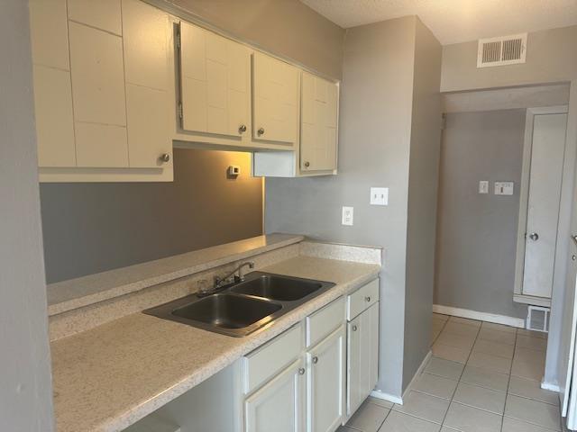 kitchen with white cabinetry, sink, and light tile patterned flooring