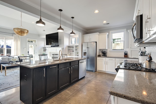 kitchen with appliances with stainless steel finishes, decorative light fixtures, sink, white cabinets, and a center island with sink