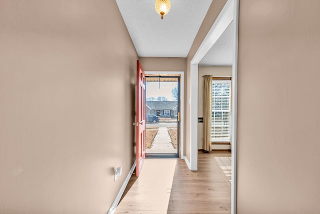 hall featuring a textured ceiling and light hardwood / wood-style flooring