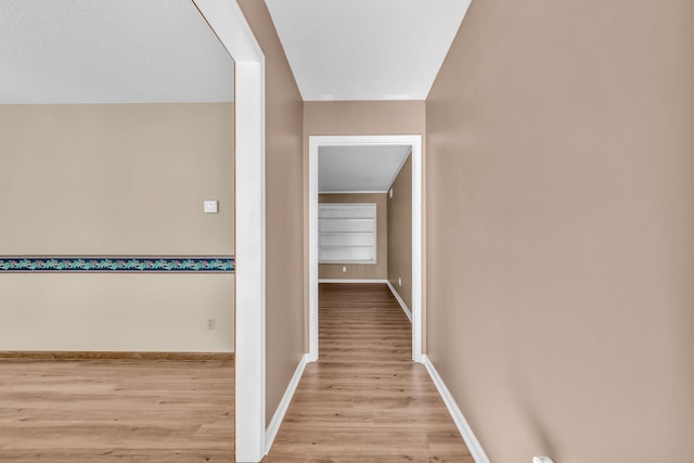 corridor with built in shelves and light hardwood / wood-style floors