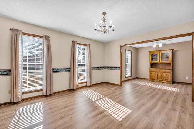 spare room with ceiling fan with notable chandelier, a textured ceiling, and light hardwood / wood-style floors