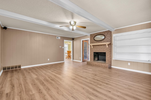 unfurnished living room featuring a fireplace, beamed ceiling, ceiling fan, a textured ceiling, and light wood-type flooring