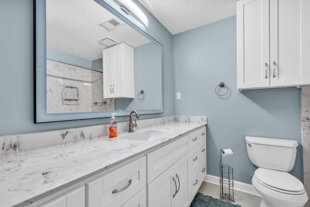 bathroom with tile patterned floors, vanity, toilet, and a textured ceiling