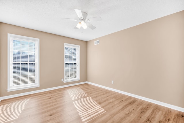 unfurnished room with ceiling fan, a textured ceiling, and light wood-type flooring