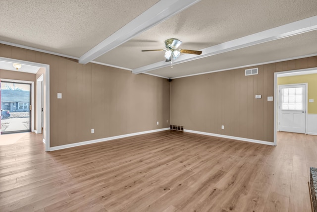 interior space with plenty of natural light, light wood-type flooring, a textured ceiling, and beam ceiling