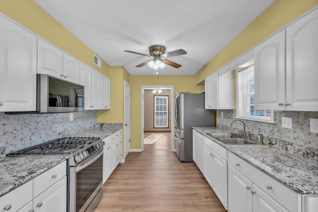 kitchen featuring tasteful backsplash, sink, white cabinets, and appliances with stainless steel finishes