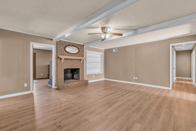 unfurnished living room featuring a brick fireplace, a textured ceiling, built in features, beamed ceiling, and ceiling fan