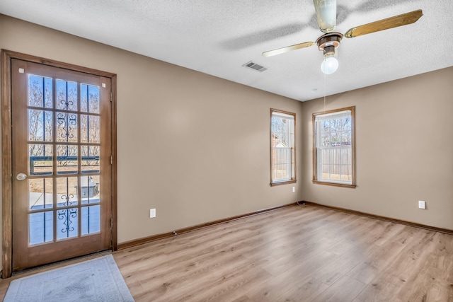 spare room with ceiling fan, light hardwood / wood-style floors, and a textured ceiling