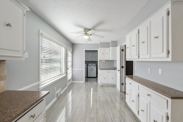 kitchen featuring ceiling fan, washing machine and dryer, and white cabinets