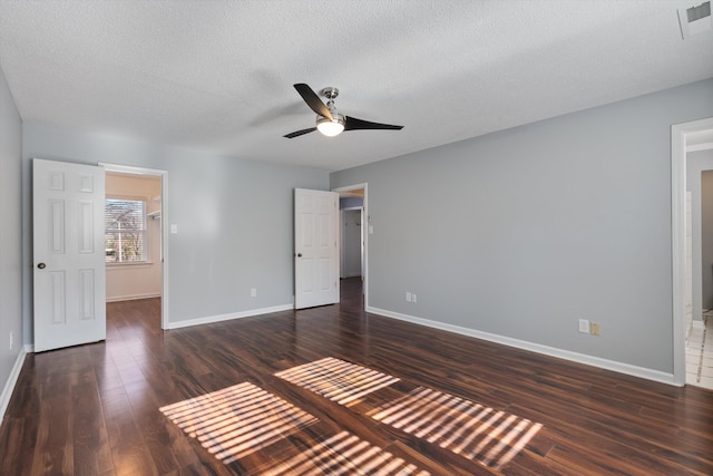 unfurnished bedroom featuring dark hardwood / wood-style flooring, a spacious closet, a textured ceiling, and ceiling fan