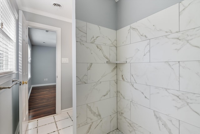 bathroom with ornamental molding and tiled shower