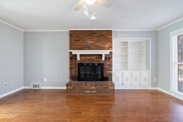 unfurnished living room with crown molding, plenty of natural light, a fireplace, and wood-type flooring