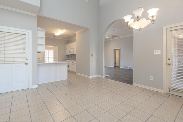 tiled spare room featuring ornamental molding and ceiling fan with notable chandelier