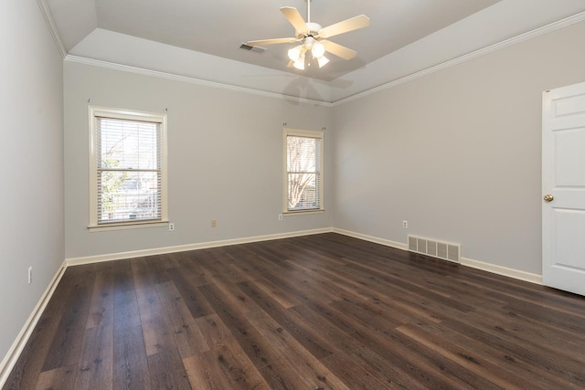 spare room with vaulted ceiling, ornamental molding, ceiling fan, a tray ceiling, and dark wood-type flooring