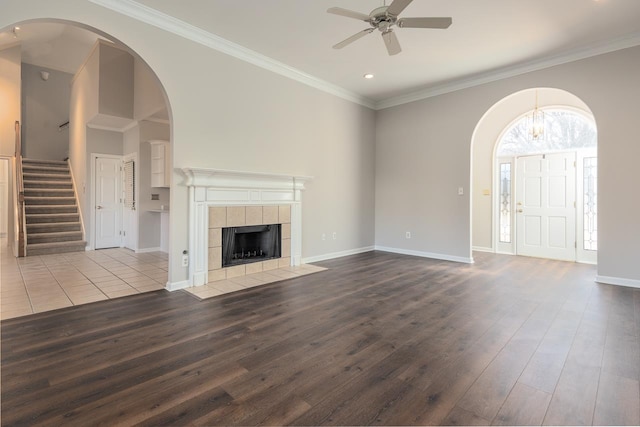 unfurnished living room with crown molding, hardwood / wood-style flooring, a tile fireplace, and ceiling fan