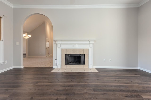 unfurnished living room featuring dark hardwood / wood-style flooring, a tiled fireplace, and crown molding