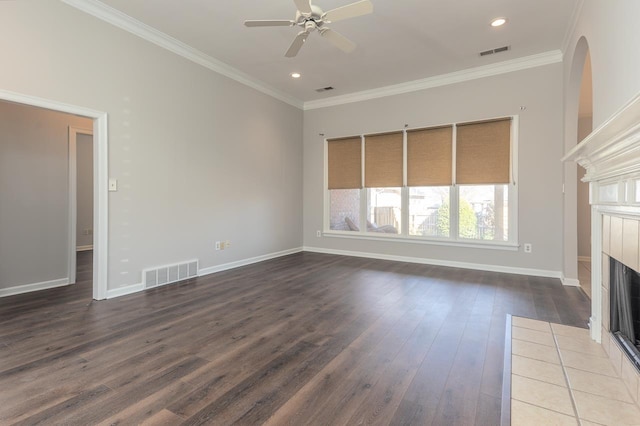 unfurnished living room featuring ceiling fan, ornamental molding, dark hardwood / wood-style floors, and a tile fireplace