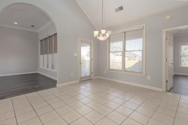 spare room with ornamental molding, vaulted ceiling, light tile patterned floors, and a chandelier