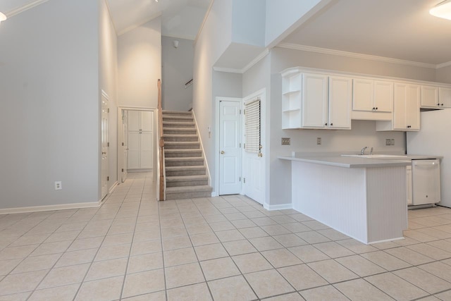 kitchen with crown molding, light tile patterned floors, dishwasher, kitchen peninsula, and white cabinets