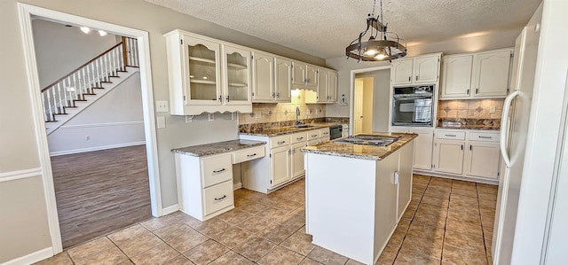 kitchen featuring dark stone counters, black appliances, a center island, and a textured ceiling