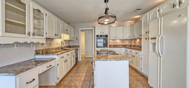 kitchen featuring black appliances, a center island, hanging light fixtures, dark stone counters, and white cabinets